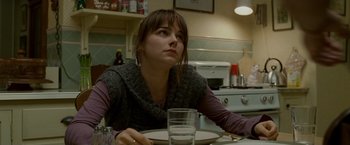 Movie still from “Edge of Darkness” (2010), directed by Martin Campbell – A woman sitting at a table with a glass of water; Close Up shot, High angle