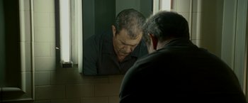 Movie still from “Edge of Darkness” (2010), directed by Martin Campbell – A man looking at his reflection in a mirror; Medium shot, Low angle