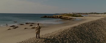 Movie still from “Edge of Darkness” (2010), directed by Martin Campbell – A man standing on a beach looking out to sea; Extreme Wide shot, High angle