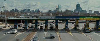 Movie still from “Edge of Darkness” (2010), directed by Martin Campbell – Cars are driving on a highway near a toll booth; Extreme Wide shot, High angle