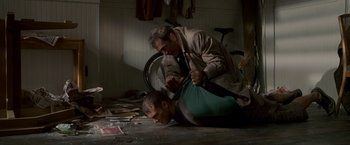 Movie still from “Edge of Darkness” (2010), directed by Martin Campbell – A man is on the ground with another man on the ground; Medium shot, Low angle