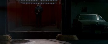 Movie still from “Edge of Darkness” (2010), directed by Martin Campbell – A man in a suit standing in front of a door way; Wide shot, Low angle