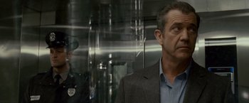 Movie still from “Edge of Darkness” (2010), directed by Martin Campbell – A man standing in front of an elevator; Close Up shot, Over the shoulder angle