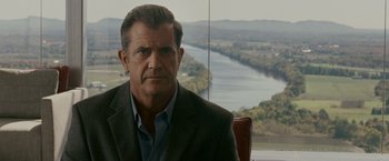 Movie still from “Edge of Darkness” (2010), directed by Martin Campbell – A man sitting in a chair in front of a river; Close Up shot, Over the shoulder angle