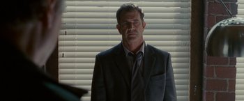 Movie still from “Edge of Darkness” (2010), directed by Martin Campbell – A man wearing a suit and tie standing in front of a window; Close Up shot, Over the shoulder angle