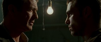 Movie still from “Edge of Darkness” (2010), directed by Martin Campbell – Two men facing each other in front of a light bulb; Close Up shot, Low angle