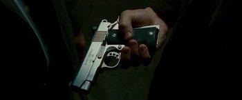Movie still from “Edge of Darkness” (2010), directed by Martin Campbell – A person holding a gun in their hand; Close Up shot, High angle