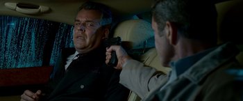 Movie still from “Edge of Darkness” (2010), directed by Martin Campbell – A man holding a gun pointed at another man in the back of a car; Close Up shot, Over the shoulder angle