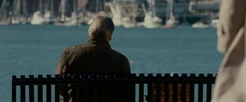Movie still from “Edge of Darkness” (2010), directed by Martin Campbell – An older man sitting on a bench looking out at the water; Medium shot, Over the shoulder angle