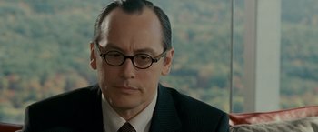 Movie still from “Edge of Darkness” (2010), directed by Martin Campbell – A man wearing a suit and glasses; Close Up shot, Over the shoulder angle