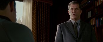 Movie still from “Edge of Darkness” (2010), directed by Martin Campbell – A man in a suit and tie standing in front of a curtain; Close Up shot, Over the shoulder angle