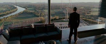 Movie still from “Edge of Darkness” (2010), directed by Martin Campbell – A man in a suit standing in front of a large window; Wide shot, Over the shoulder angle