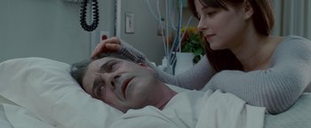 Movie still from “Edge of Darkness” (2010), directed by Martin Campbell – A man laying in a hospital bed with a woman touching his head; Close Up shot, Over the shoulder angle
