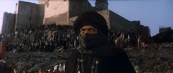 Movie still from “El Cid” (1961), directed by Anthony Mann – A man wearing a black mask and a black hat; Medium shot, Low angle
