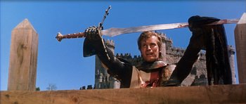 Movie still from “El Cid” (1961), directed by Anthony Mann – A man holding a sword in front of a castle; Medium shot, Low angle