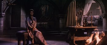 Movie still from “El Cid” (1961), directed by Anthony Mann – A woman sitting on a chair in a dark room; Wide shot, Low angle