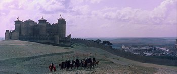 Movie still from “El Cid” (1961), directed by Anthony Mann – A group of people riding horses near a castle; Extreme Wide shot, Low angle
