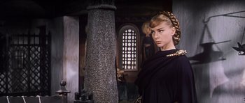 Movie still from “El Cid” (1961), directed by Anthony Mann – A woman standing next to a pillar in a room; Close Up shot, Low angle