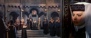 Movie still from “El Cid” (1961), directed by Anthony Mann – A group of people dressed in medieval garb in front of a building; Wide shot, High angle