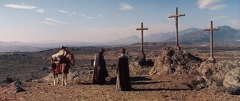 Movie still from “El Cid” (1961), directed by Anthony Mann – Two women in black capes standing in front of a cross; Extreme Wide shot, Low angle