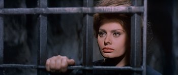 Movie still from “El Cid” (1961), directed by Anthony Mann – A beautiful woman with brown hair looking through the bars of a jail cell; Close Up shot, Low angle