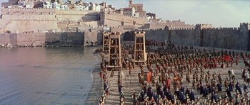 Movie still from “El Cid” (1961), directed by Anthony Mann – A crowd of people standing on top of a sandy beach; Extreme Wide shot, High angle