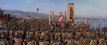 Movie still from “El Cid” (1961), directed by Anthony Mann – A large group of people dressed as roman legionnaires in front of a castle; Extreme Wide shot, High angle