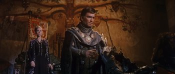 Movie still from “El Cid” (1961), directed by Anthony Mann – A man dressed as a medieval knight standing in front of a painting; Medium shot, Over the shoulder angle