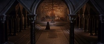Movie still from “El Cid” (1961), directed by Anthony Mann – A woman dressed in medieval garb stands in front of an ornate mural; Extreme Wide shot, High angle