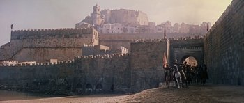 Movie still from “El Cid” (1961), directed by Anthony Mann – A man riding a horse next to a castle; Extreme Wide shot, Low angle
