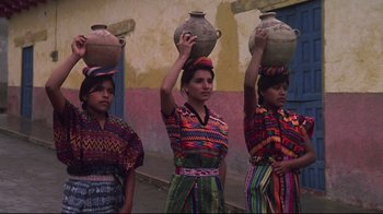 Movie still from “El Norte” (1983), directed by Gregory Nava – A group of women in colorful clothing carrying pots on their heads; Medium shot, Low angle