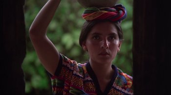 Movie still from “El Norte” (1983), directed by Gregory Nava – A woman in a colorful shirt holding a bowl on her head; Close Up shot, Low angle