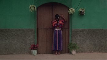 Movie still from “El Norte” (1983), directed by Gregory Nava – A woman standing in front of a green building; Wide shot, High angle
