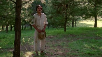 Movie still from “El Norte” (1983), directed by Gregory Nava – A man standing in the middle of a forest holding a hat; Medium shot, Low angle