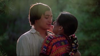 Movie still from “El Norte” (1983), directed by Gregory Nava – A man and a woman kissing each other in a forest; Medium shot, Low angle