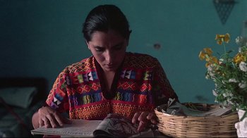 Movie still from “El Norte” (1983), directed by Gregory Nava – A woman sitting at a table looking at a book; Medium shot, Low angle