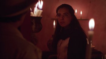 Movie still from “El Norte” (1983), directed by Gregory Nava – A woman standing in front of candles in a room; Close Up shot, Over the shoulder angle