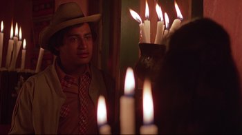 Movie still from “El Norte” (1983), directed by Gregory Nava – A man wearing a cowboy hat standing in front of candles; Close Up shot, Over the shoulder angle