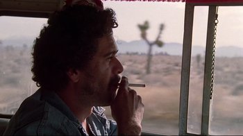 Movie still from “El Norte” (1983), directed by Gregory Nava – A man smoking a cigarette while looking out a window; Close Up shot, Low angle