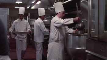 Movie still from “El Norte” (1983), directed by Gregory Nava – A group of chefs preparing food inside of a kitchen; Medium shot, Low angle