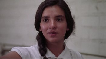 Movie still from “El Norte” (1983), directed by Gregory Nava – A woman with a braid is looking at the camera; Close Up shot, Low angle