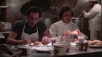 Movie still from “El Norte” (1983), directed by Gregory Nava – Two men sitting at a table eating food; Medium shot, Low angle