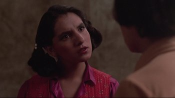 Movie still from “El Norte” (1983), directed by Gregory Nava – A woman in a pink shirt looking at her reflection in a mirror; Close Up shot, Over the shoulder angle