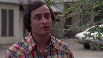 Movie still from “El Norte” (1983), directed by Gregory Nava – A man in a plaid shirt is standing in front of a tree; Close Up shot, Low angle