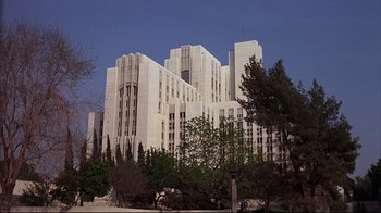 Movie still from “El Norte” (1983), directed by Gregory Nava – A large white building sitting next to a forest; Extreme Wide shot, Low angle