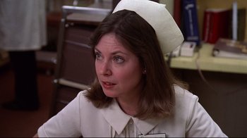 Movie still from “El Norte” (1983), directed by Gregory Nava – A woman wearing a nurse's hat sitting in front of a chair; Close Up shot, Low angle