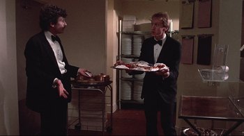 Movie still from “El Norte” (1983), directed by Gregory Nava – A man in a tuxedo holding a tray of food; Medium shot, Over the shoulder angle