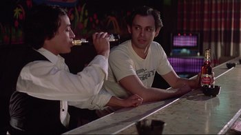 Movie still from “El Norte” (1983), directed by Gregory Nava – Two men sitting at a bar drinking beer; Medium shot, Over the shoulder angle