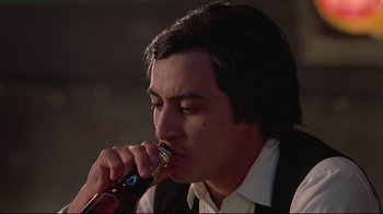 Movie still from “El Norte” (1983), directed by Gregory Nava – A man in a black vest is holding a microphone; Close Up shot, Low angle