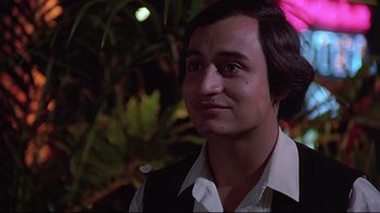Movie still from “El Norte” (1983), directed by Gregory Nava – A young man with long black hair wearing a white shirt; Close Up shot, Low angle